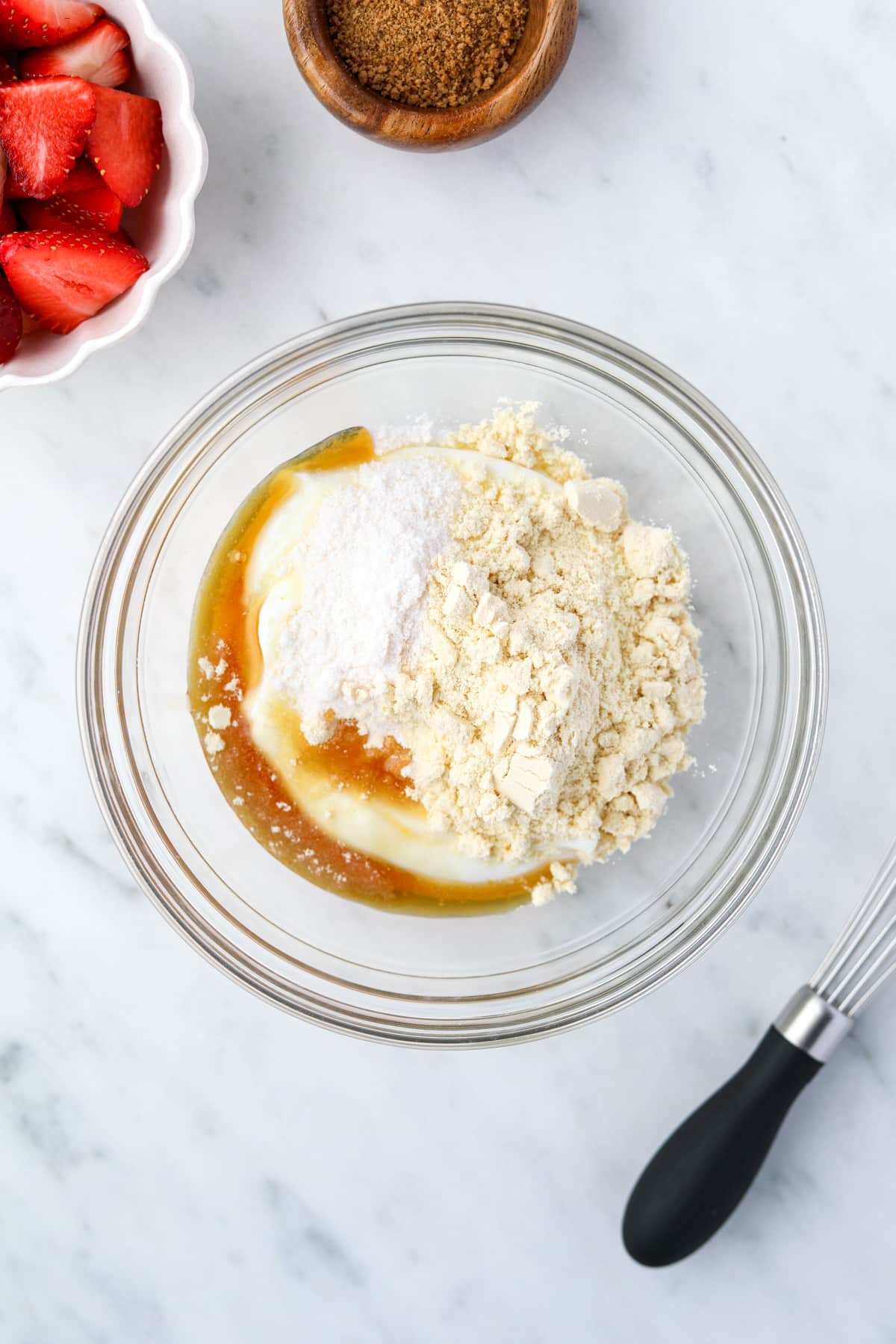 A bowl with yogurt, protein powder, maple syrup, pudding mix, and vanilla inside.