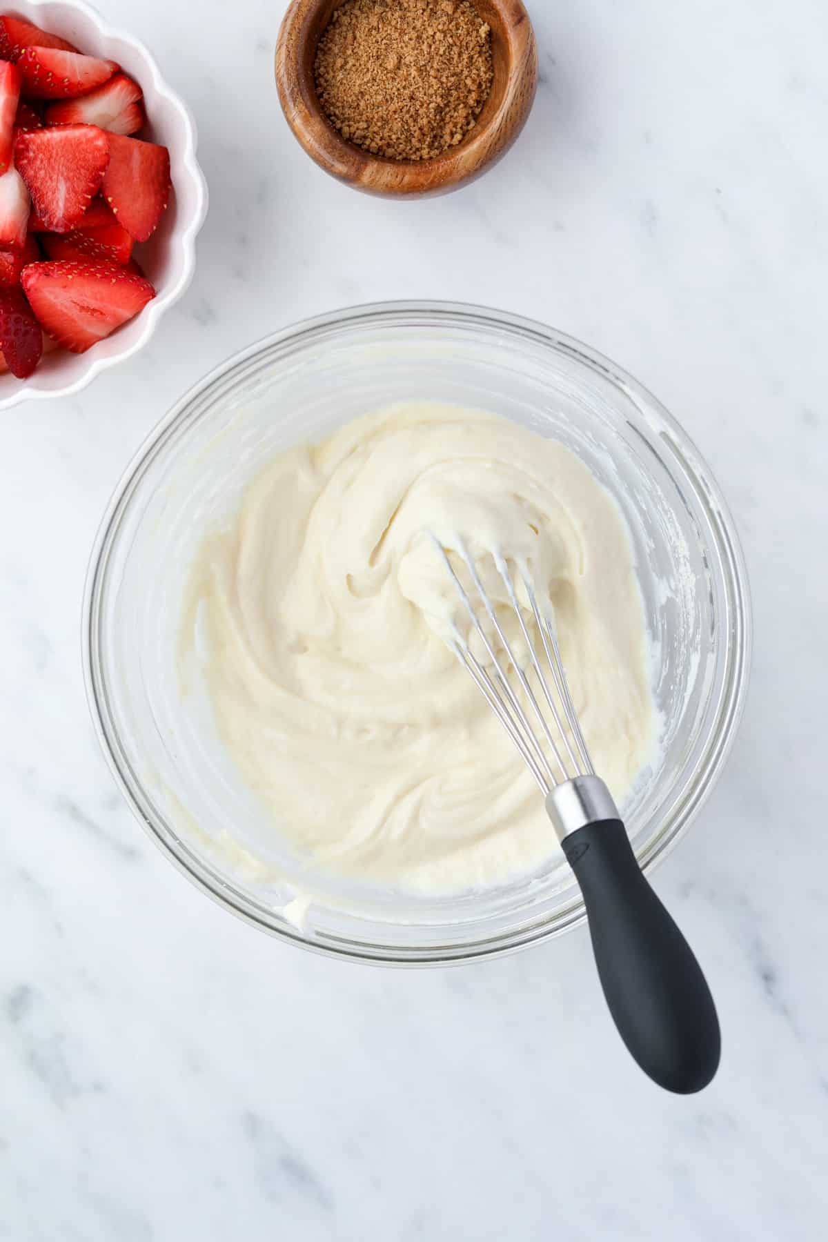 A bowl with creamy yogurt and a mini whisk.