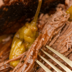 A close up of shredded pot roast soaking in juices.