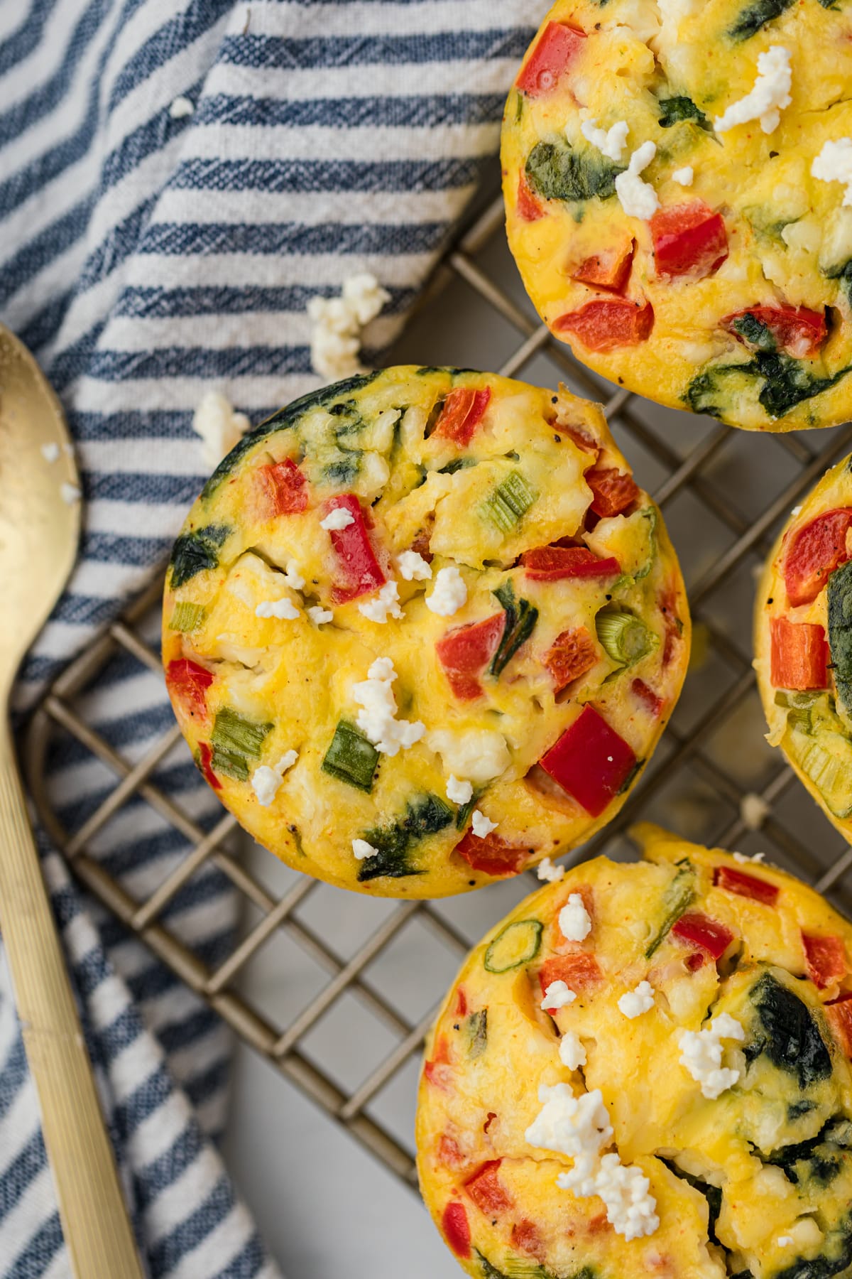 A feta and spinach egg muffin cooling on a wire rack.