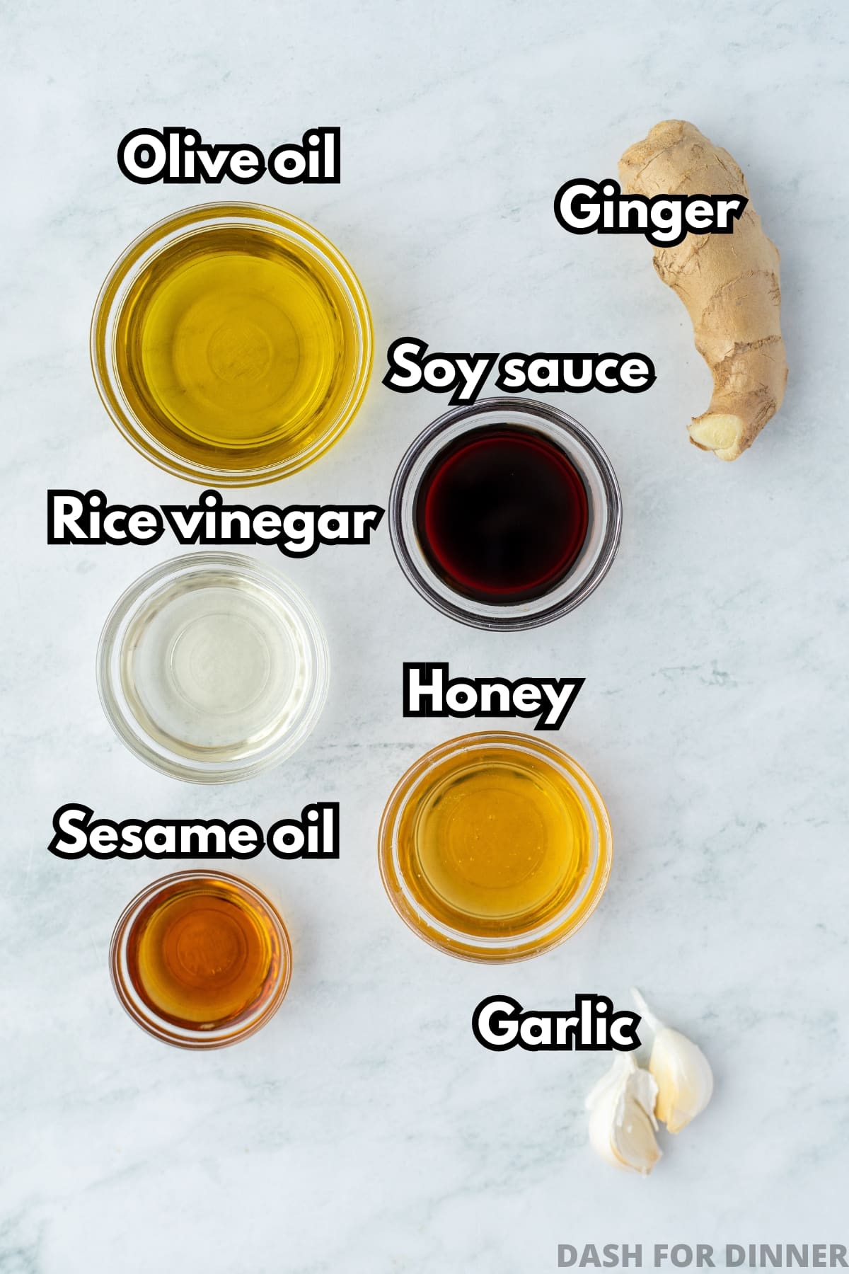 The ingredients needed to make sesame ginger dressing, including olive oil, sesame oil, soy sauce, ginger, and garlic.