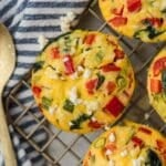 A mini frittata on a wire rack, filled with spinach, red pepper, and feta cheese.