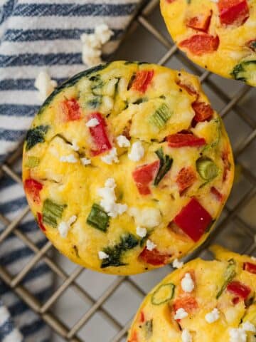 A mini frittata on a wire rack, filled with spinach, red pepper, and feta cheese.