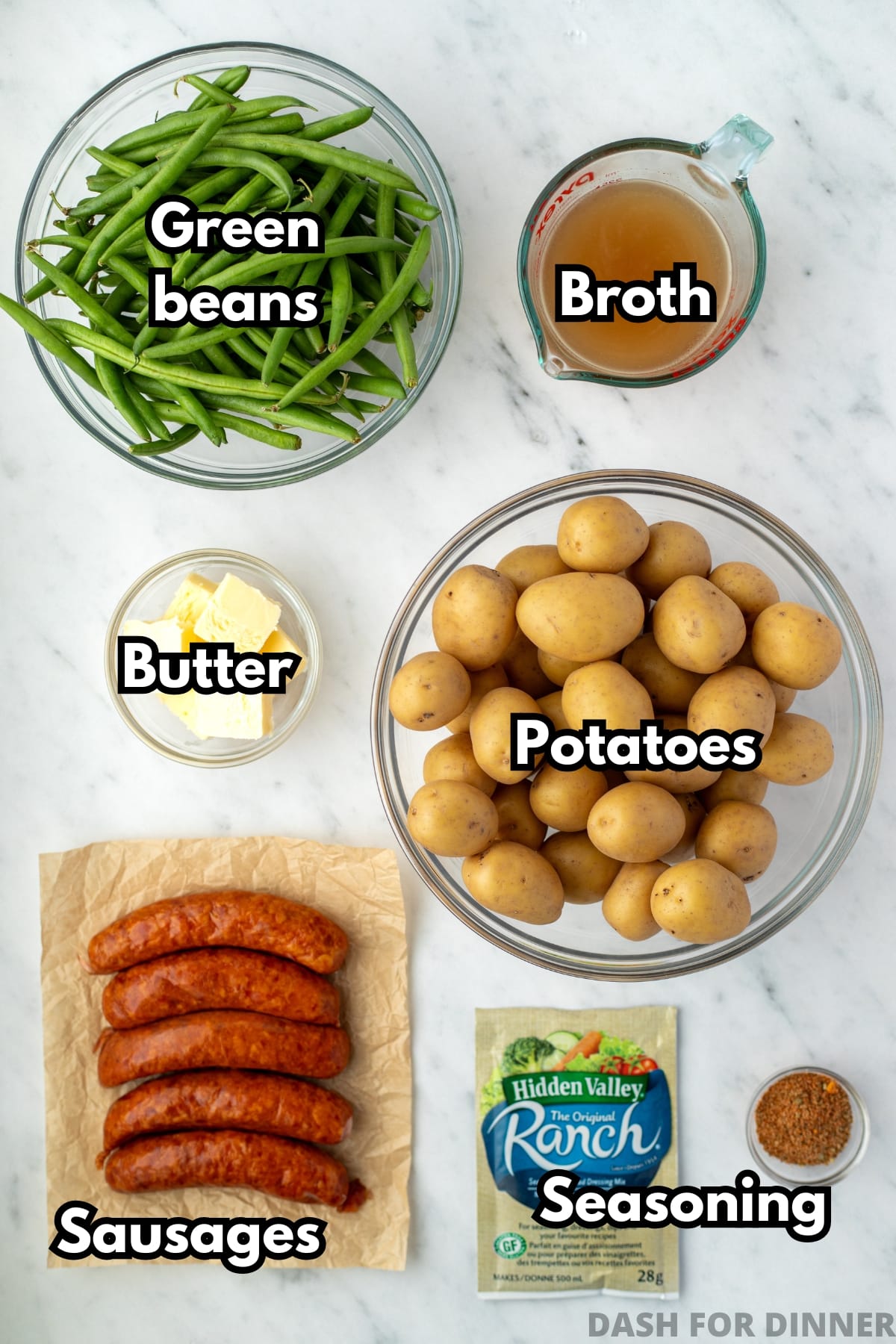 The ingredients needed to make potatoes and sausage in the slow cooker: baby potatoes, sausage, green beans, butter, and seasoning.
