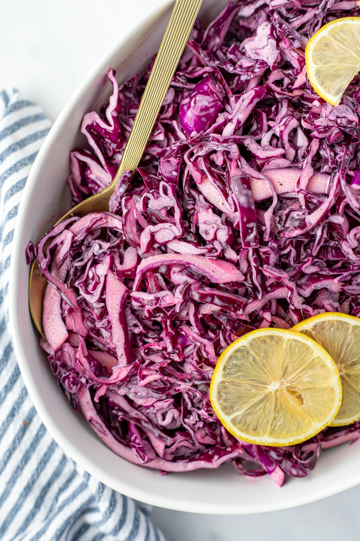 A spoon taking a portion of red cabbage salad from a large bowl.