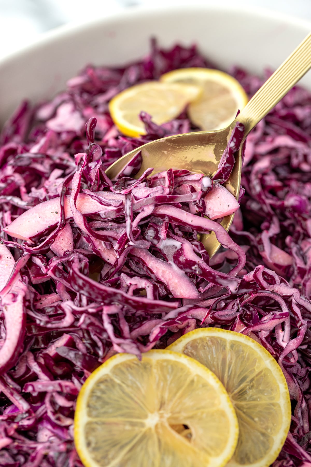 A spoon taking a portion of red cabbage salad from a bowl.