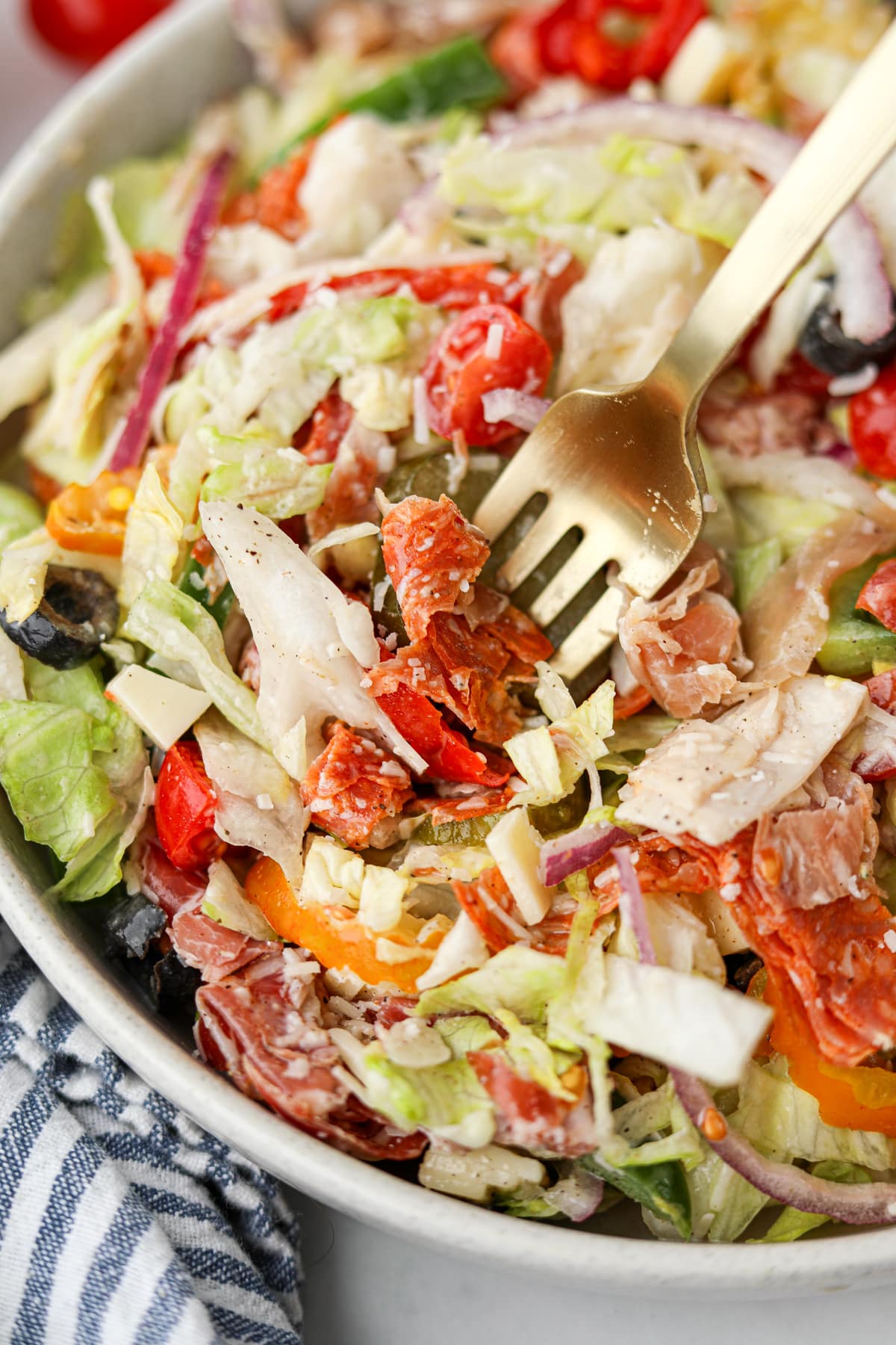 A fork taking a portion of salad from a bowl.