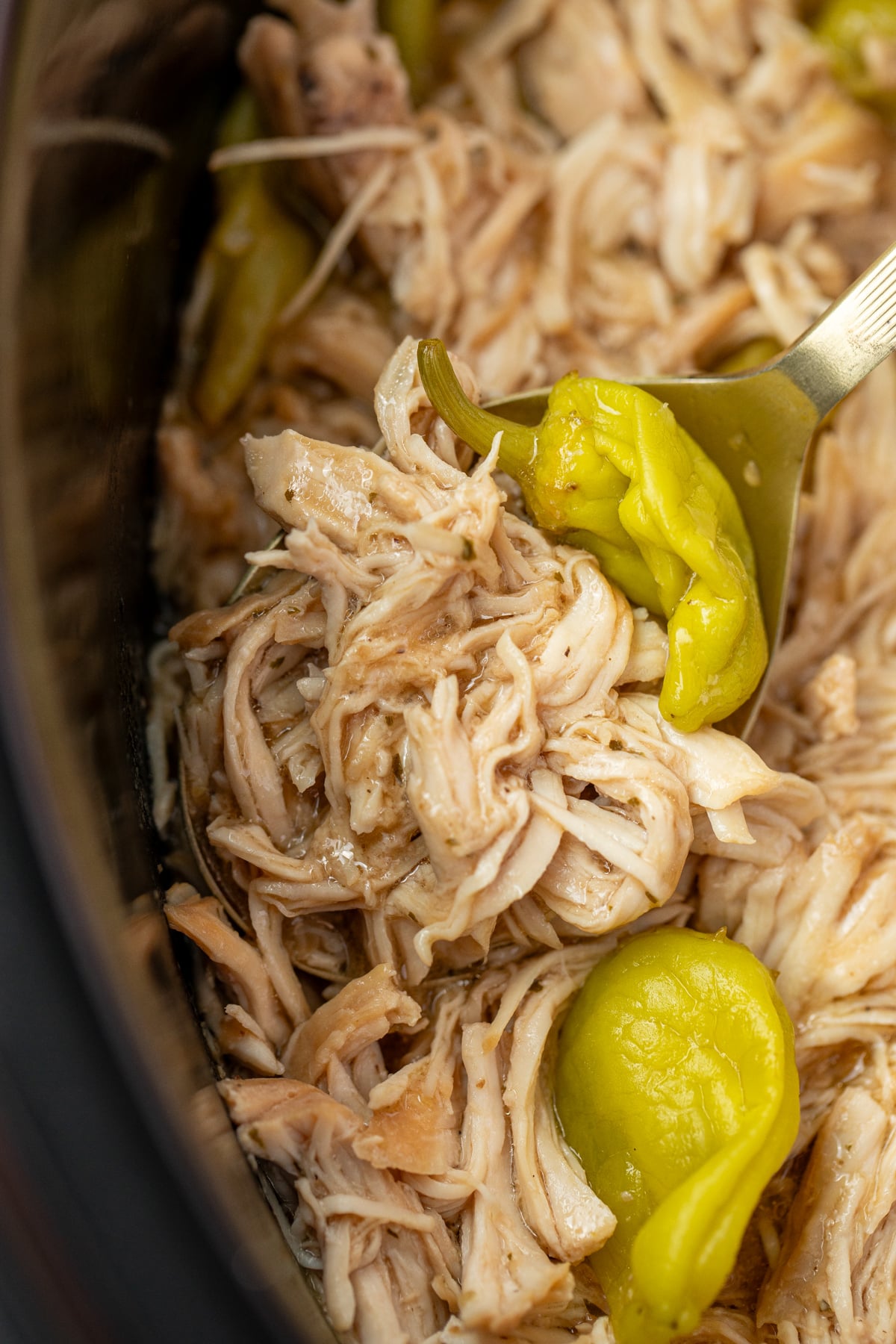 Scooping shredded chicken from a slow cooker.