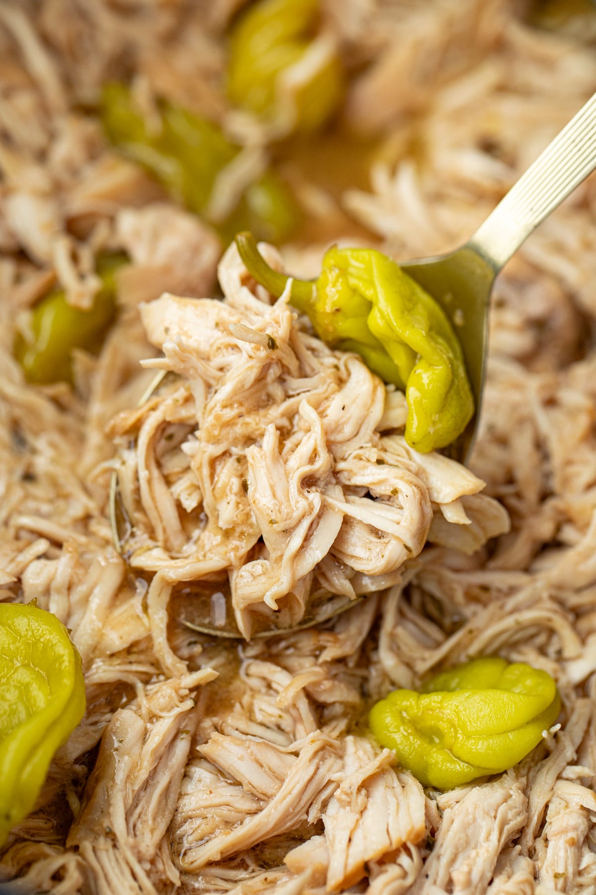 Scooping shredded chicken from a large slow cooker.
