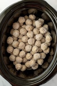 A slow cooker filled with frozen meatballs.