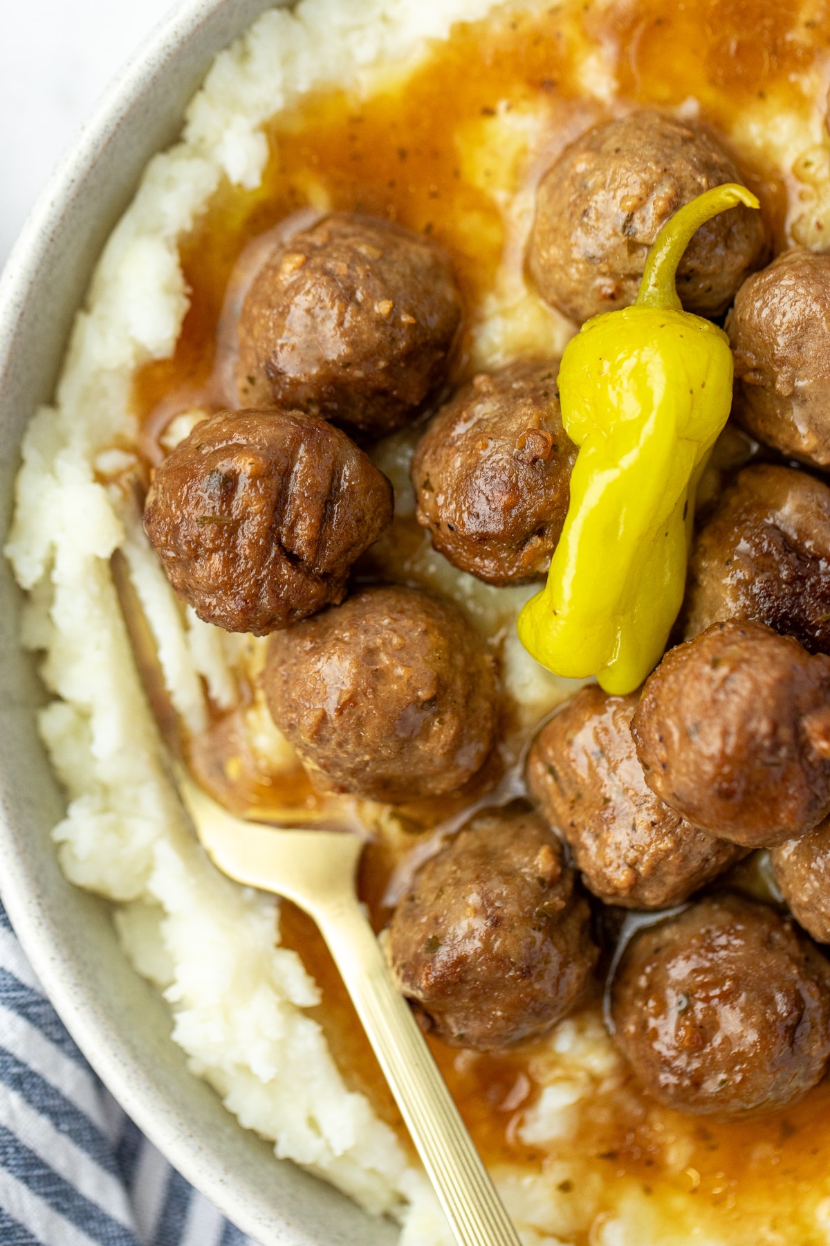 Mashed potatoes topped with meatballs and a thin sauce.