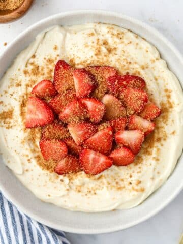 A bowl of fluffy yogurt topped with sliced strawberries and a sprinkling of graham cracker crumbs.