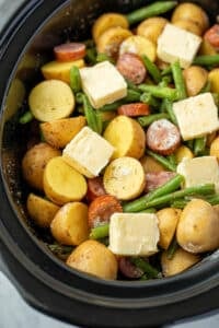 A slow cooked filled with vegetables and smoked sausage topped with butter.
