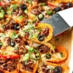 Lifting mini pepper nachos from a sheet pan.
