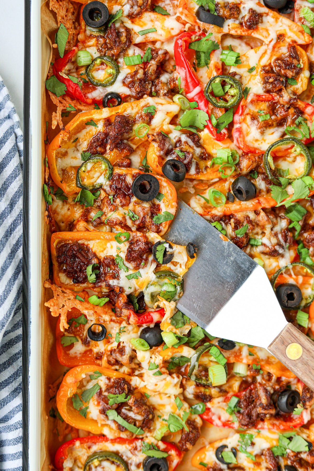 A sheet pan of bell pepper nachos with a small spatula lifting some from the pan.