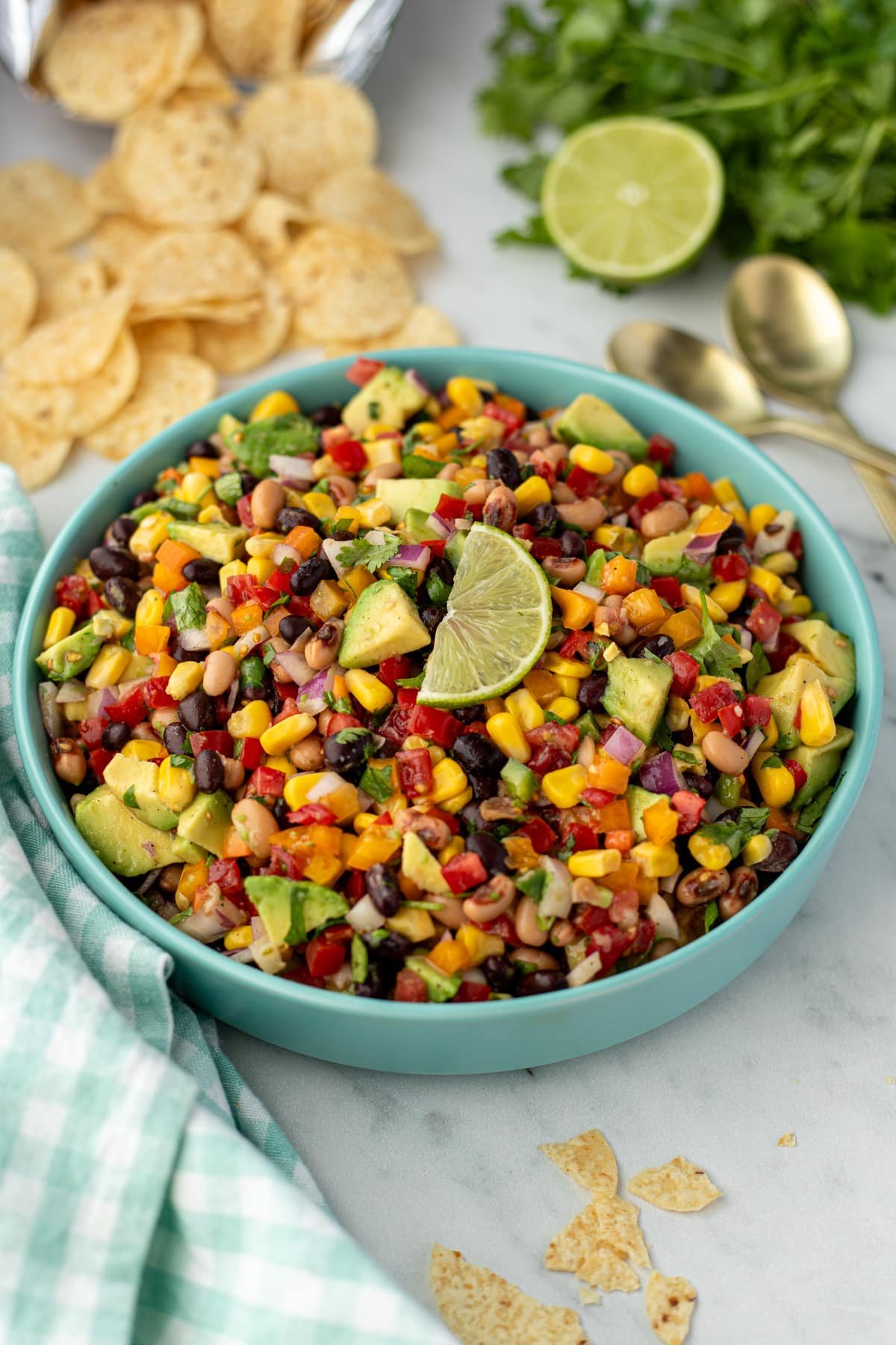 A bowl filled with cowboy caviar with tortilla chips in the background.