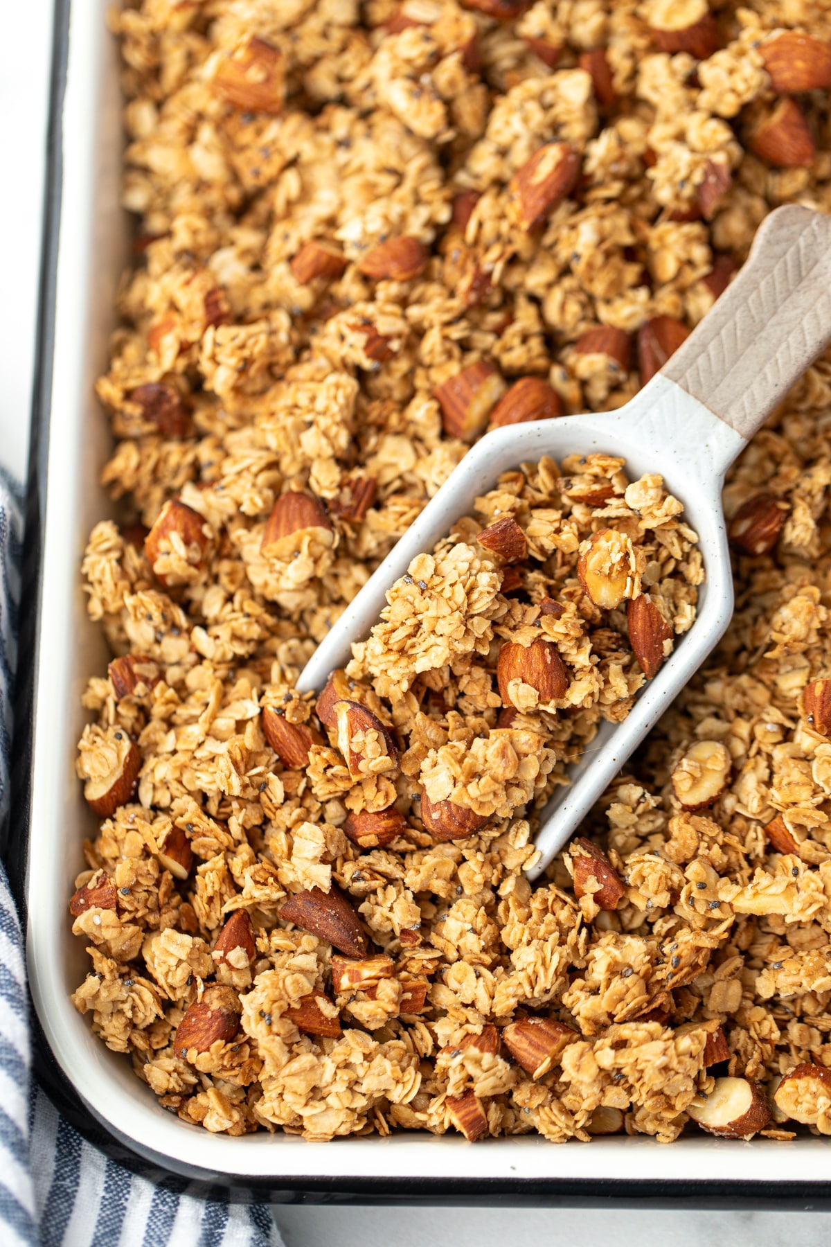 A scoop taking a portion of granola from a sheet pan.