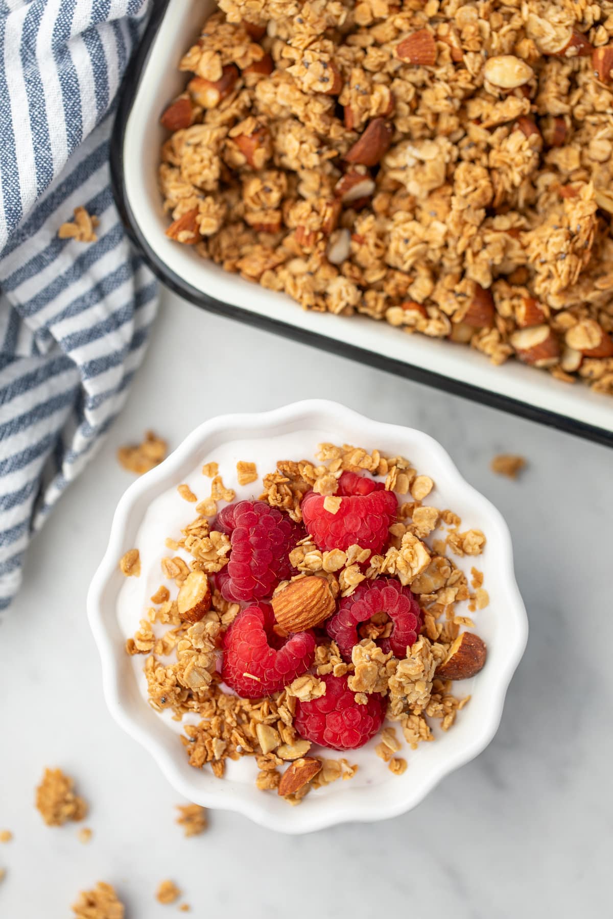 A small bowl of yogurt topped with raspberries and a sprinkling of granola.