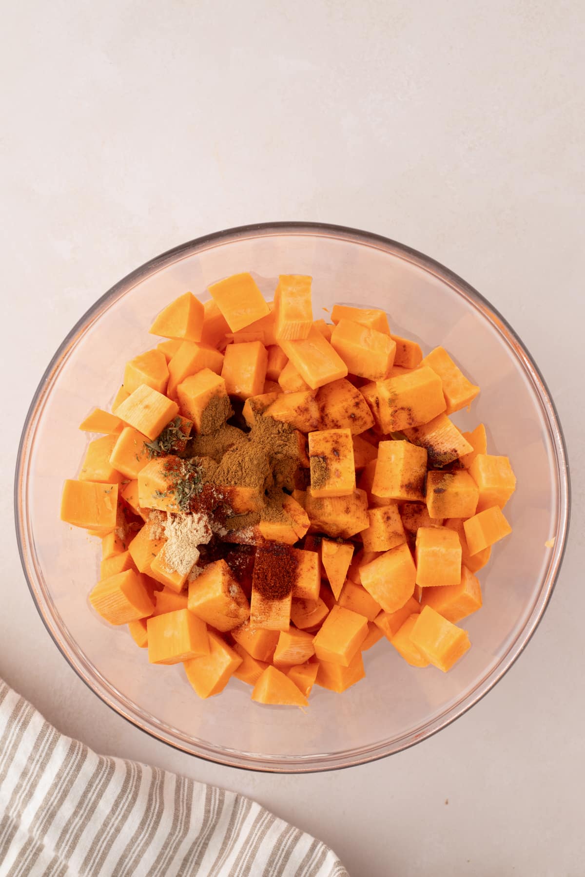 A bowl of cubed sweet potatoes with seasonings sprinkled on top.
