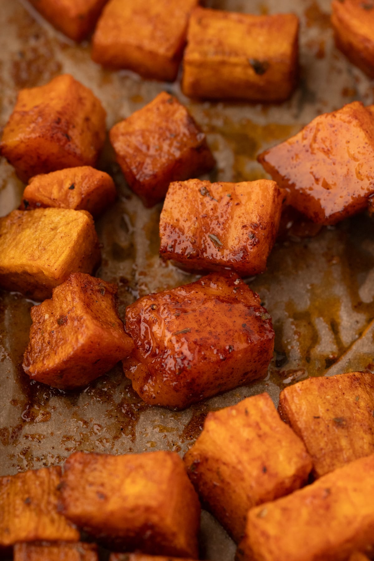 A close up of sweet potato cubes on a sheet pan, glazed with seasoning and oil.