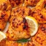 Seasoned and chicken thighs garnished wtih lemon wedges and fresh dill.