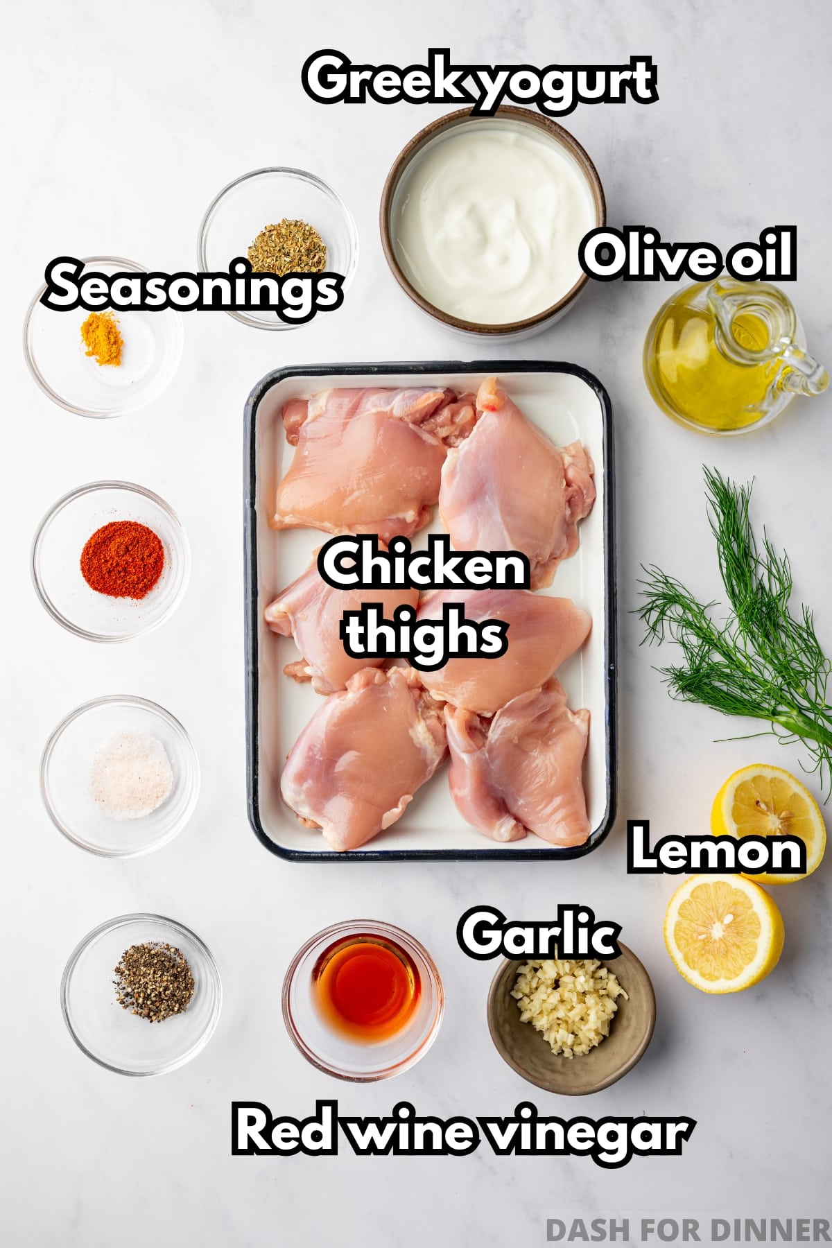 The ingredients needed to make greek yogurt chicken, including seasonings, lemon, garlic, and chicken thighs.