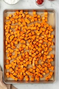 A sheet pan with seasoned sweet potato cubes.