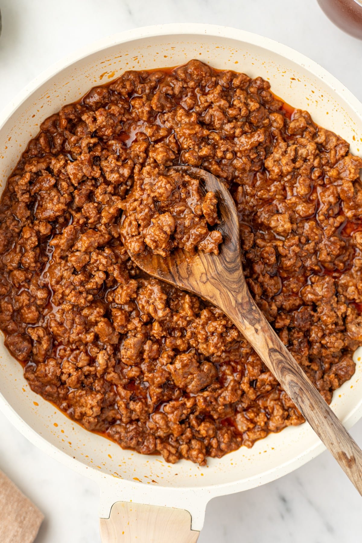 A skillet filled with saucy ground beef that has been cooked.