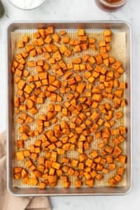 Roasted sweet potato cubes on a sheet pan.