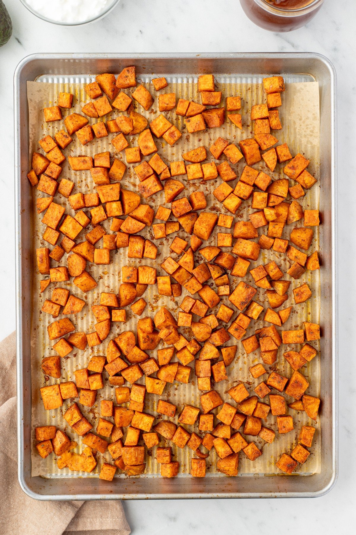 Roasted sweet potato cubes on a sheet pan.