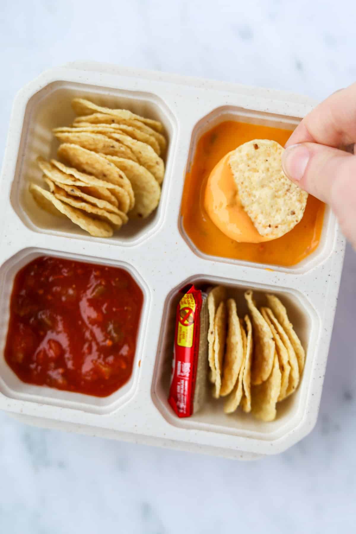 Dipping tortilla chips into queso cheese sauce.