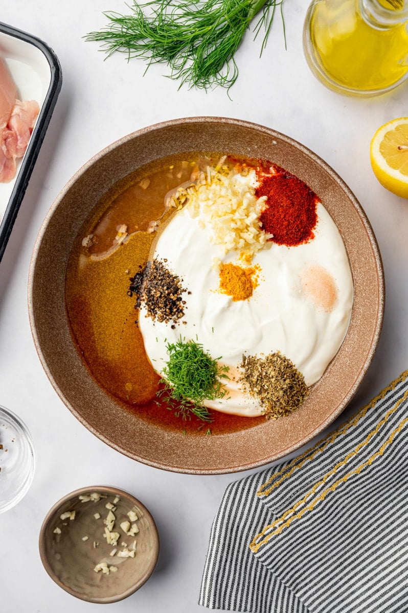 A bowl filled with oil, yogurt, and seasonings.