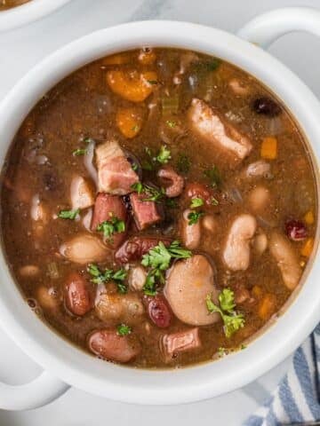 A bowl of soup filled with juicy beans and ham chunks.