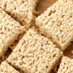 Rice krispie squares with gooey strands connecting each other.
