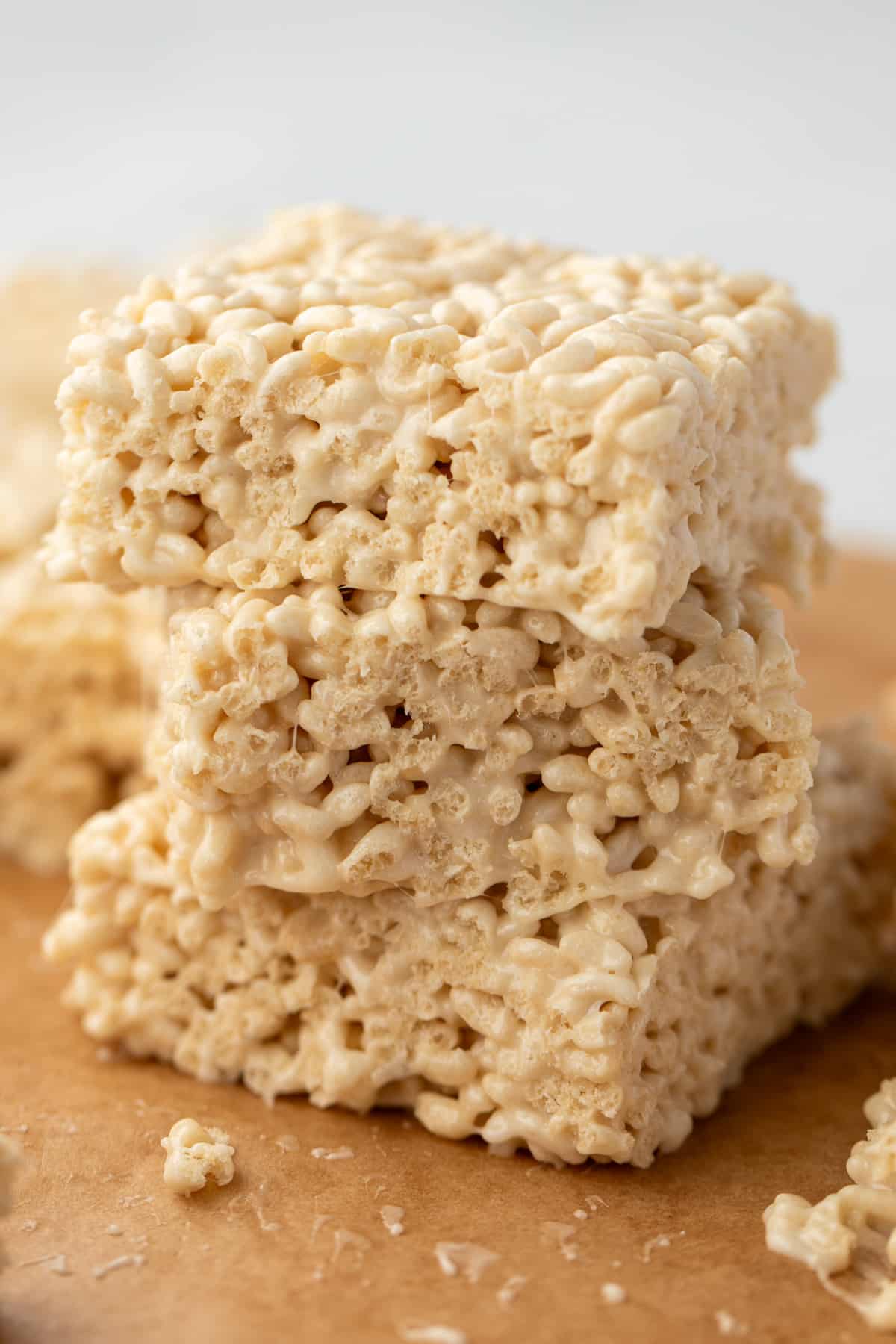 A stack of three rice cereal treats resting on parchment paper.