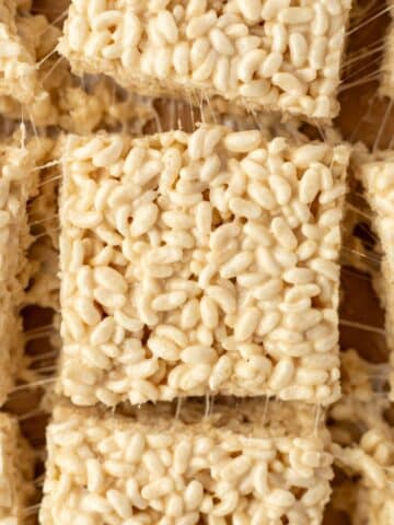 Rice cereal treats sliced into squares, resting on top of parchment paper.