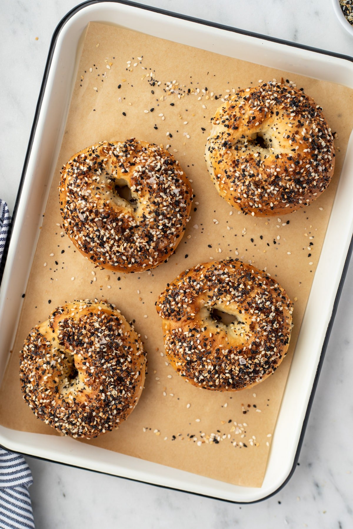 A baking tray with four everything bagels laid out.