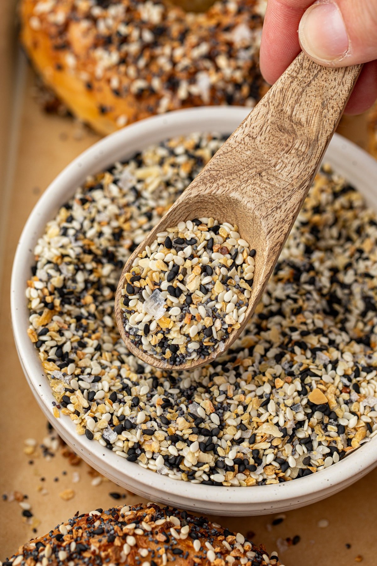 A small spoon taking everything bagel seasoning from a bowl.