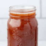 A jar of hot honey with a honey dipper on the counter.