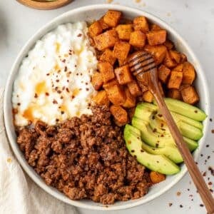 A bowl filled with sweet potatoes, cottage cheese, and ground beef.