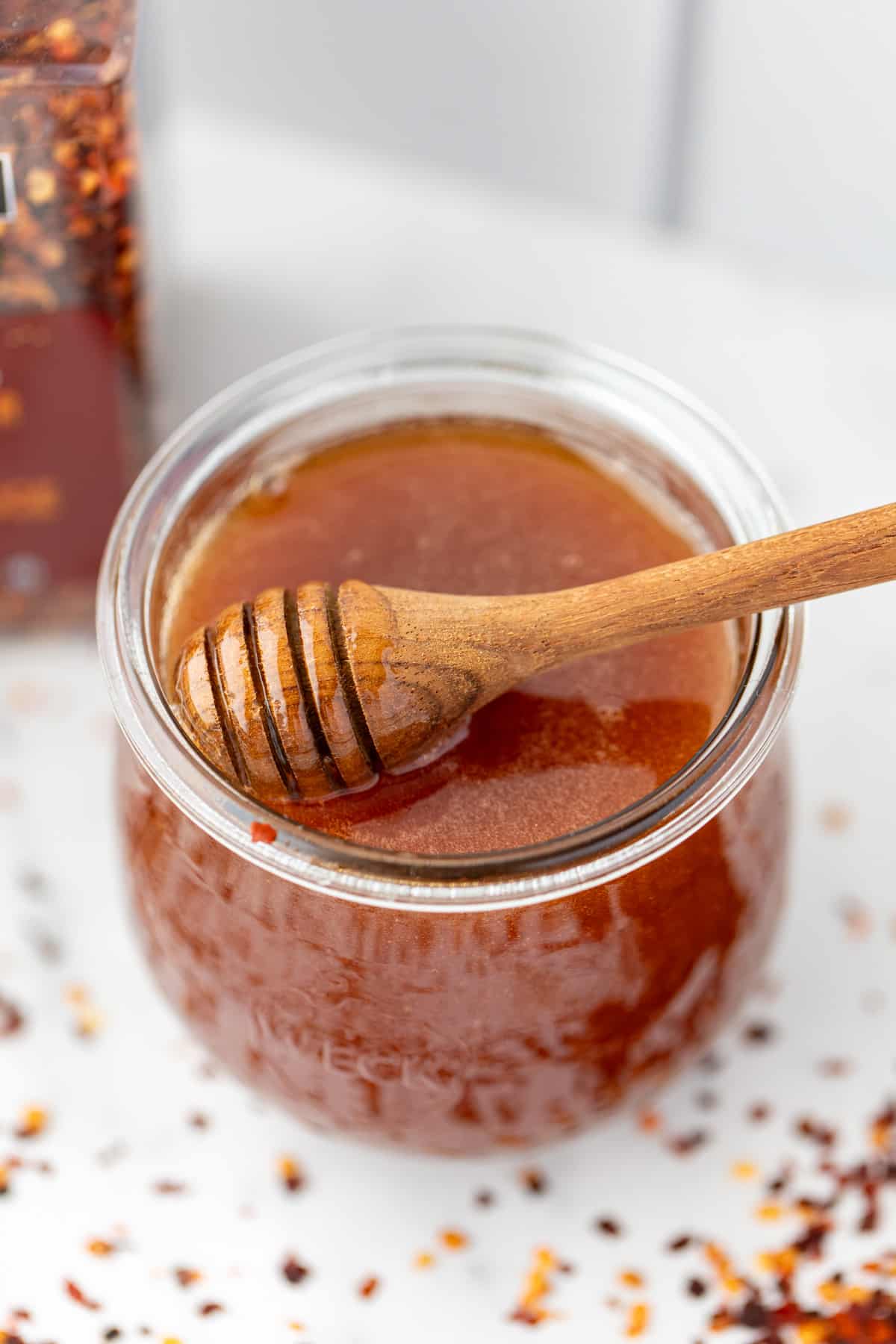 A jar of honey with a honey dipper in the jar.