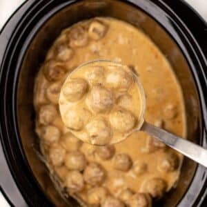 A ladleful of Swedish meatballs with creamy sauce.