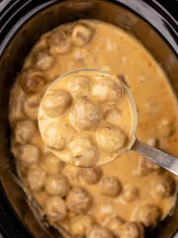 A ladleful of Swedish meatballs with creamy sauce.