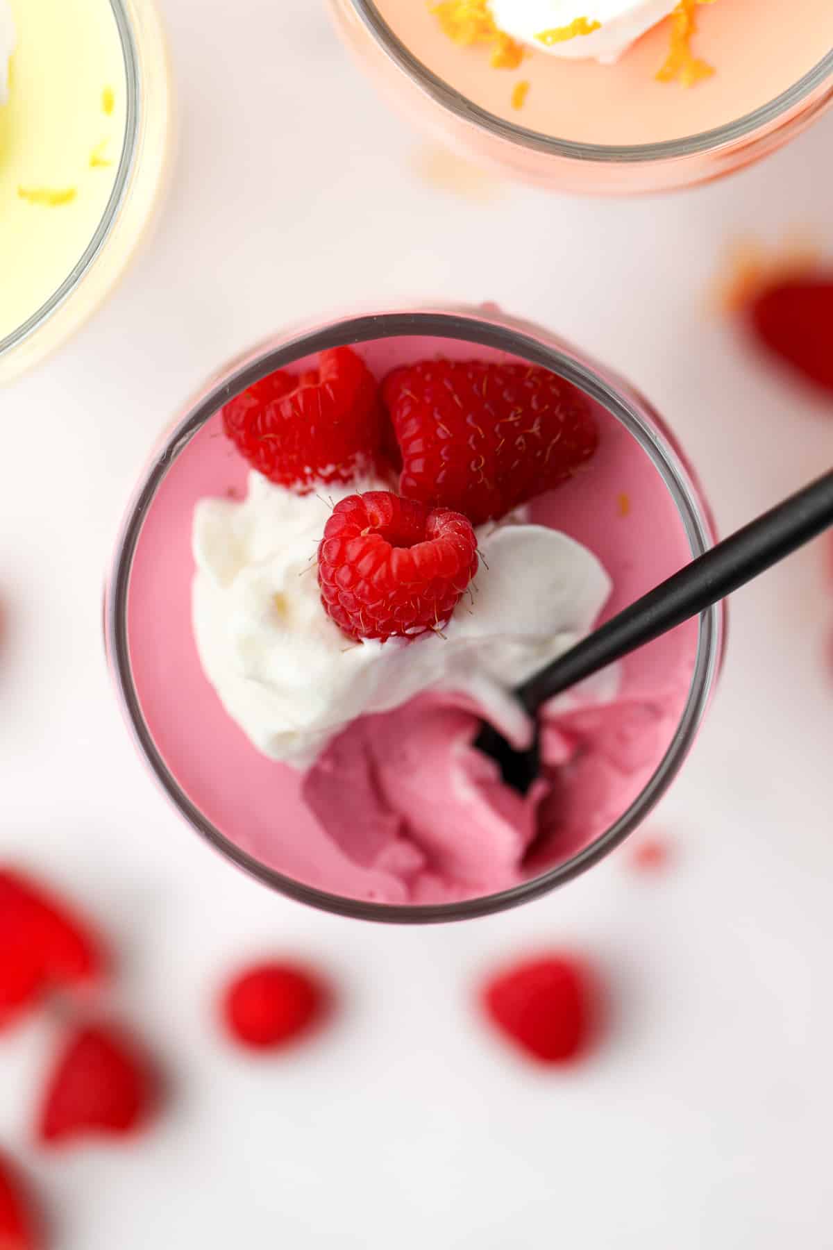 A small parfait glassed filled with protein mousse, topped wtih whipped cream and raspberries.