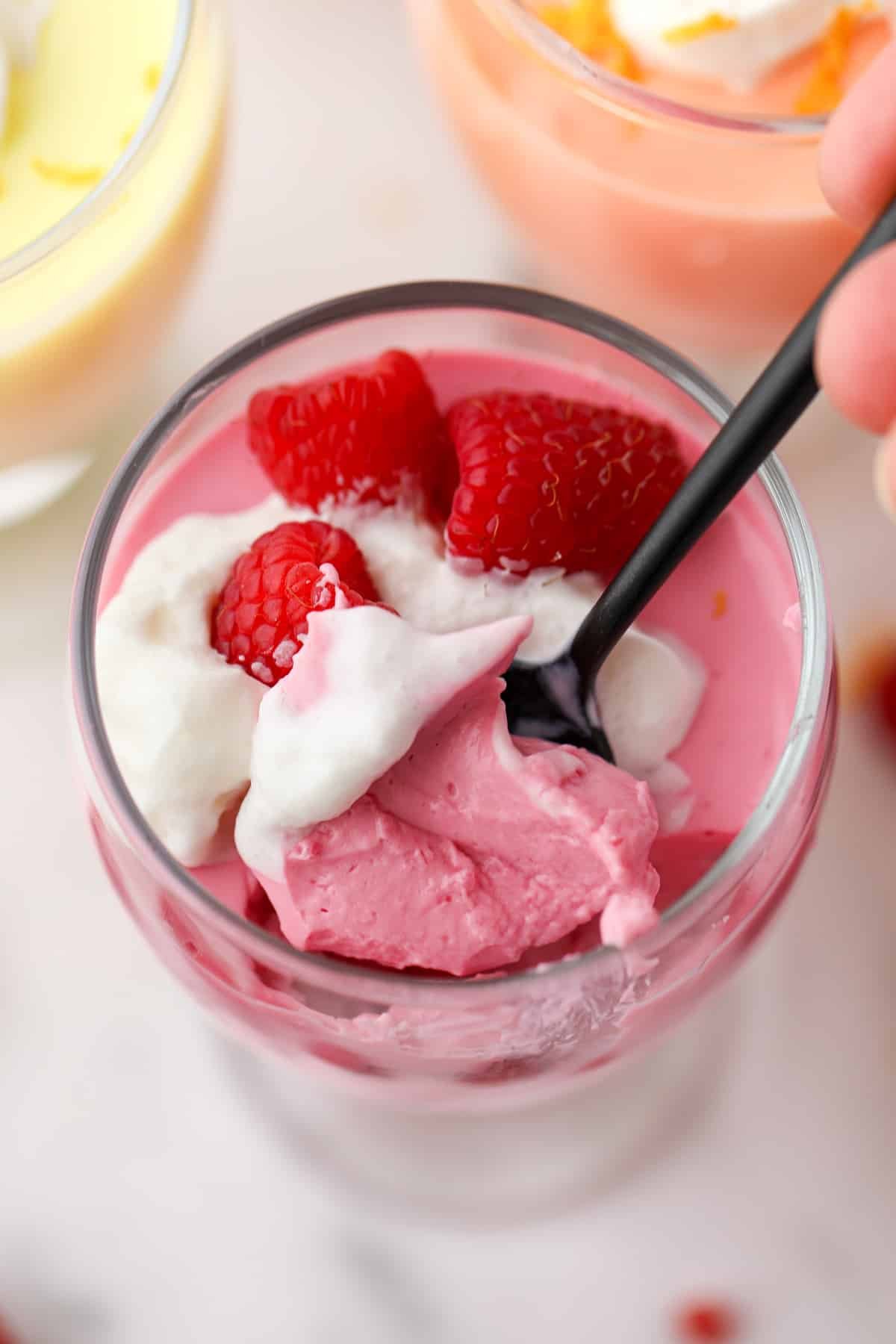 Taking a spoonful of yogurt mousse from a parfait glass.