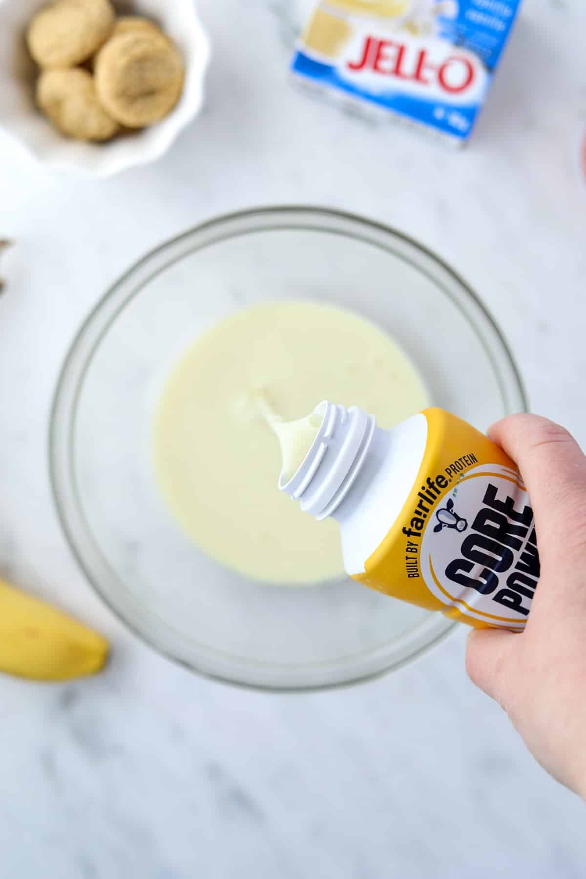 Pouring a protein shake into a glass bowl.