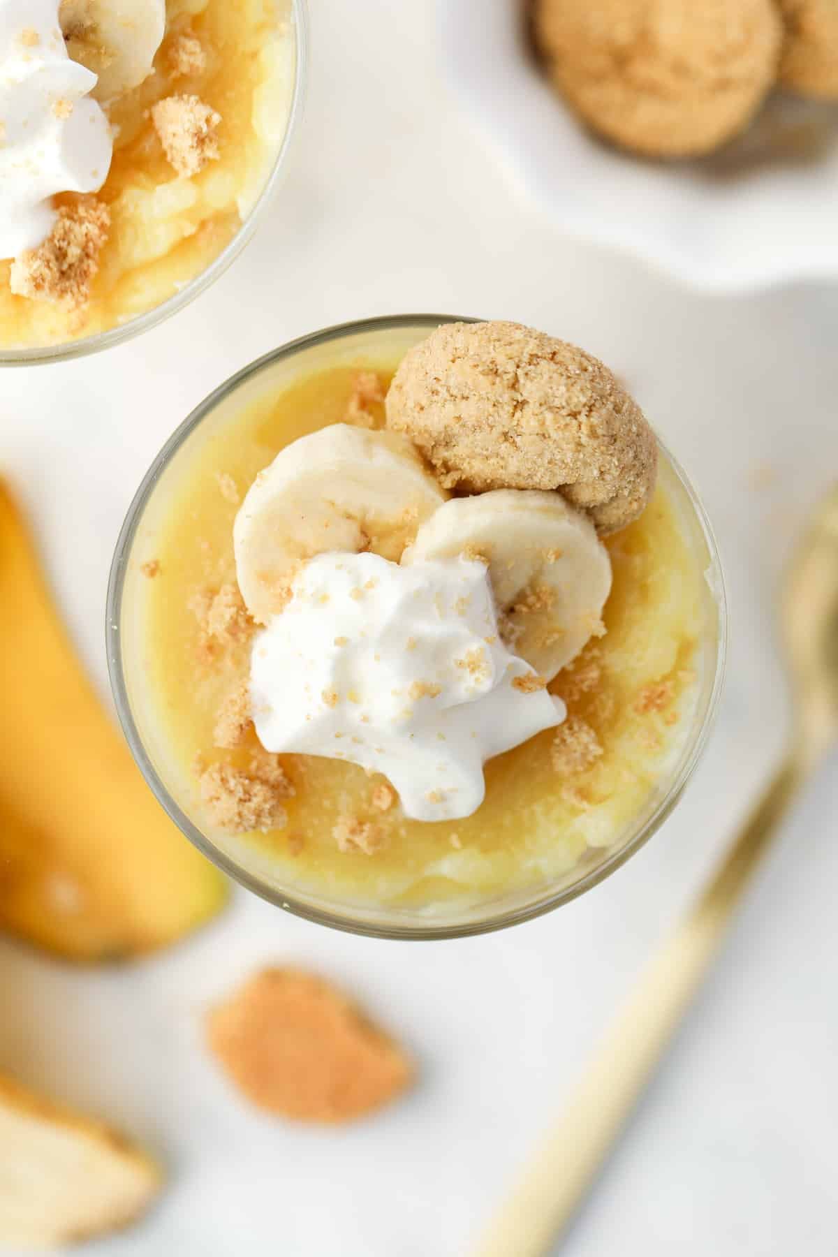 A cup of banana pudding topped with whipped cream and a few slices of banana.