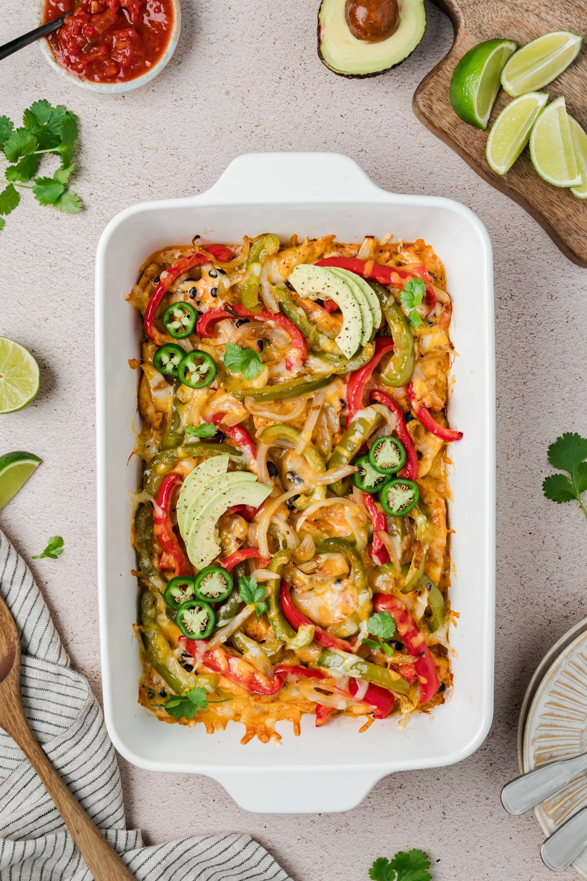 A baking dish filled with chicken and bell pepper casserole, topped with avocado.