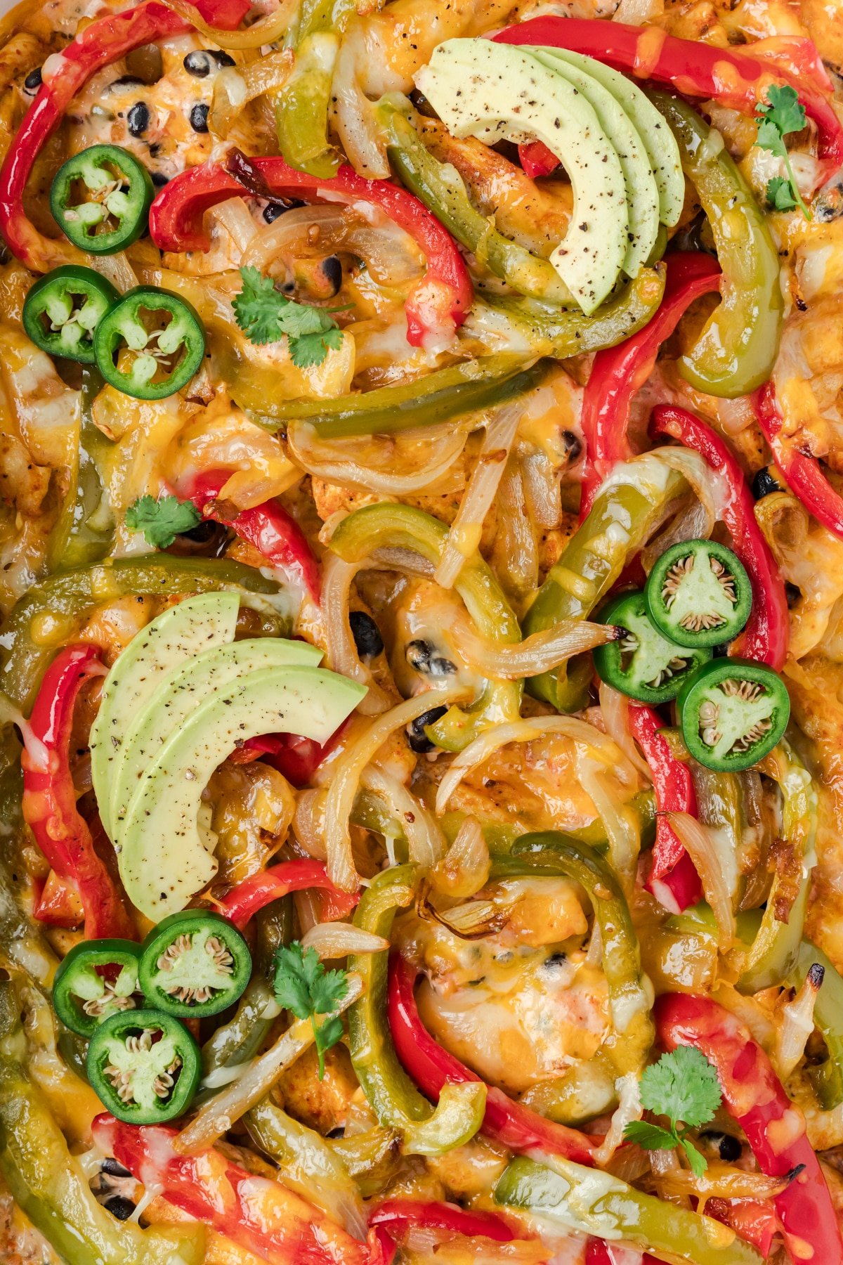 A close up of a casserole featuring peppers, onions, and chicken.