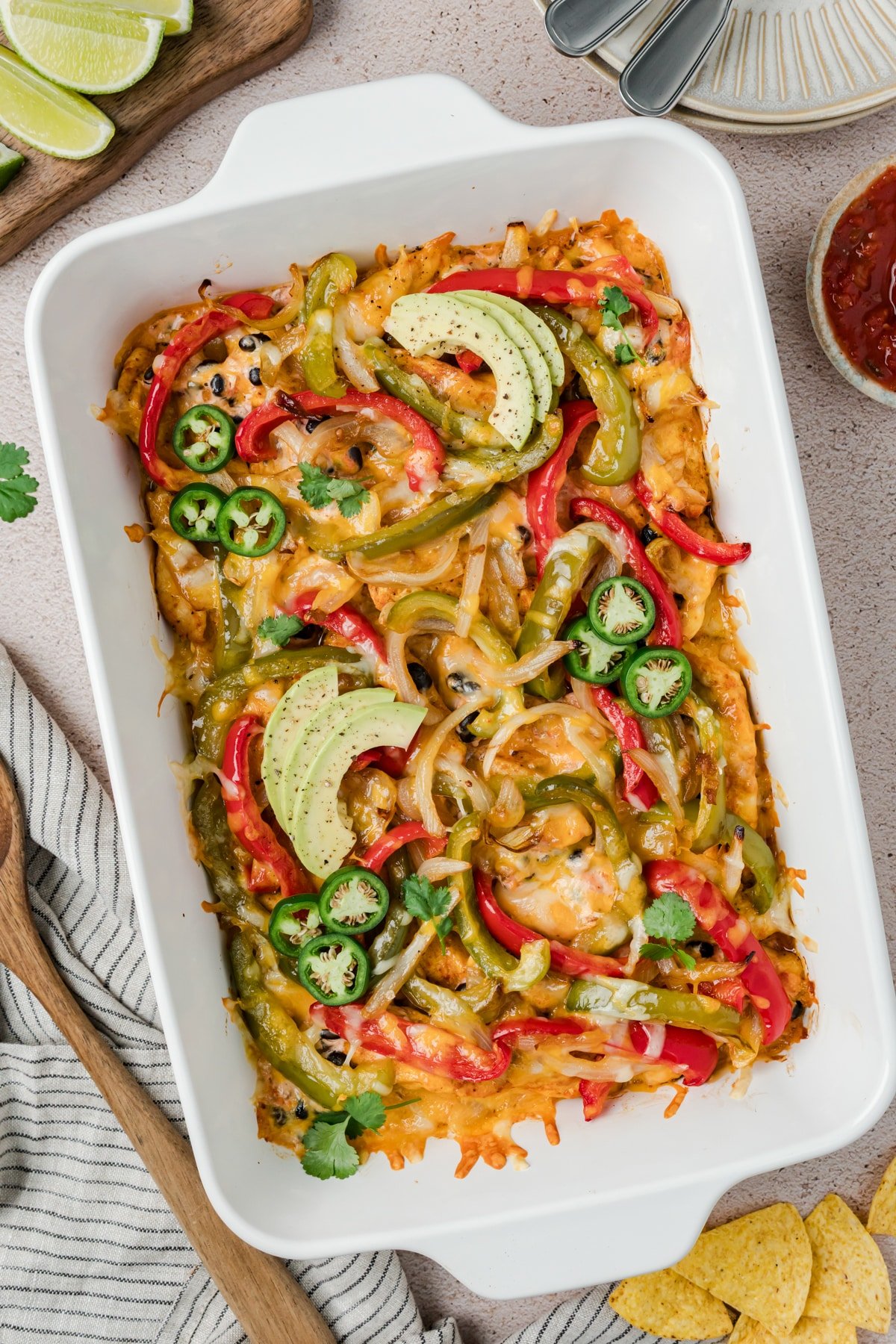 A baking dish filled with peppers, avocado, melted cheese, and chicken.